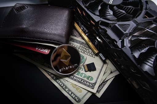 An image of a wallet, micro SD card, ethereum coin, a GPU and a couple varying domination dollar bills all in one shot